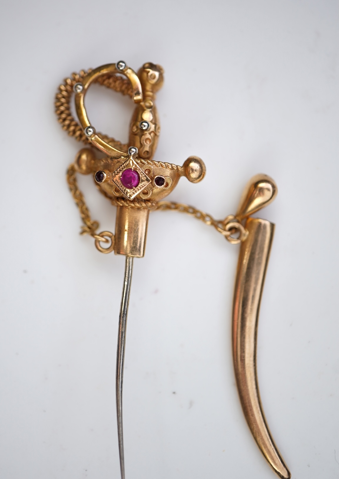 A gold and synthetic ruby jabot pin